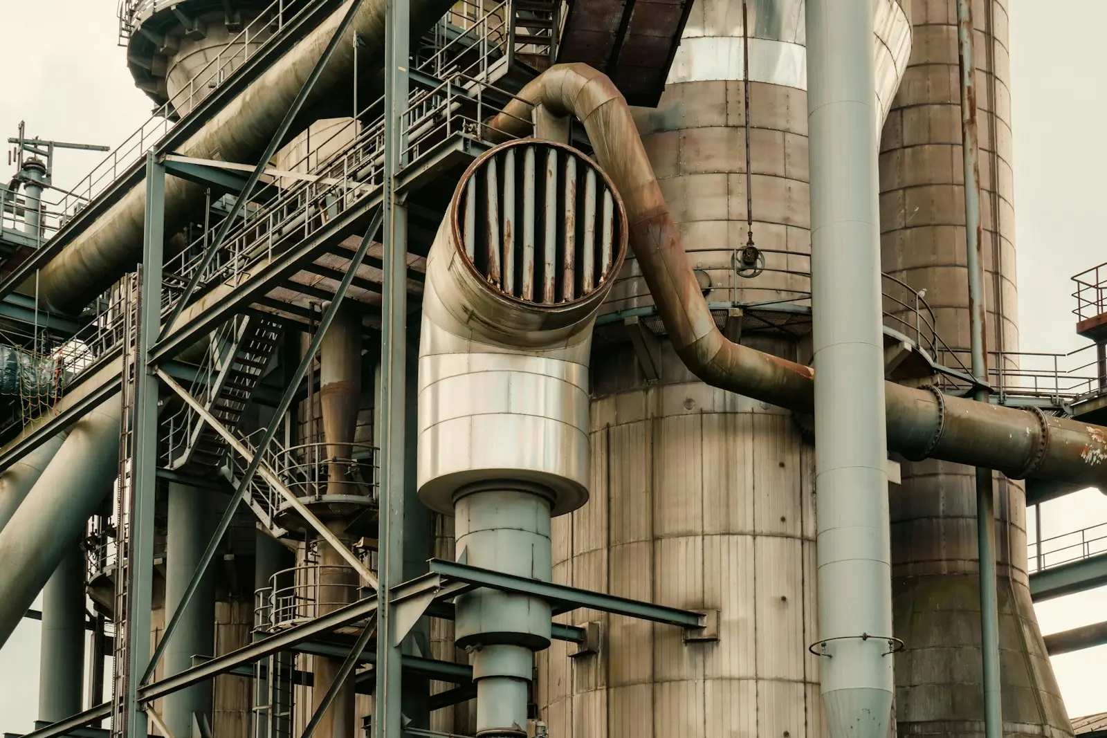 Industrial plant exterior: large-diameter ductwork, breeching and stacks on a steel structure
